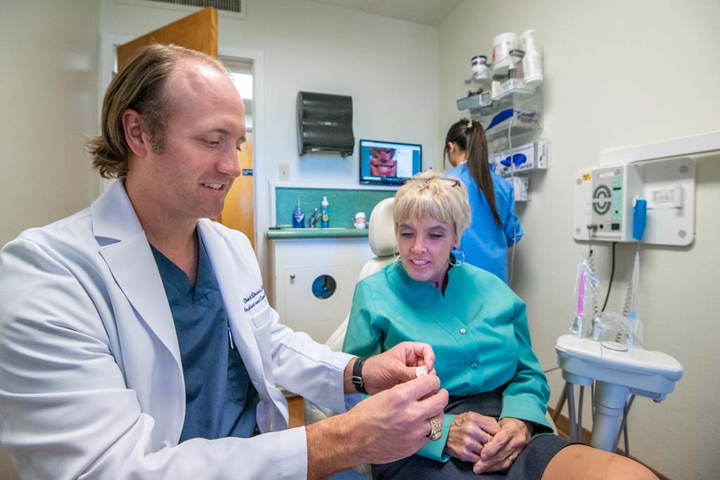 Dr Damon showing a patient a dental bridge in fort worth tx